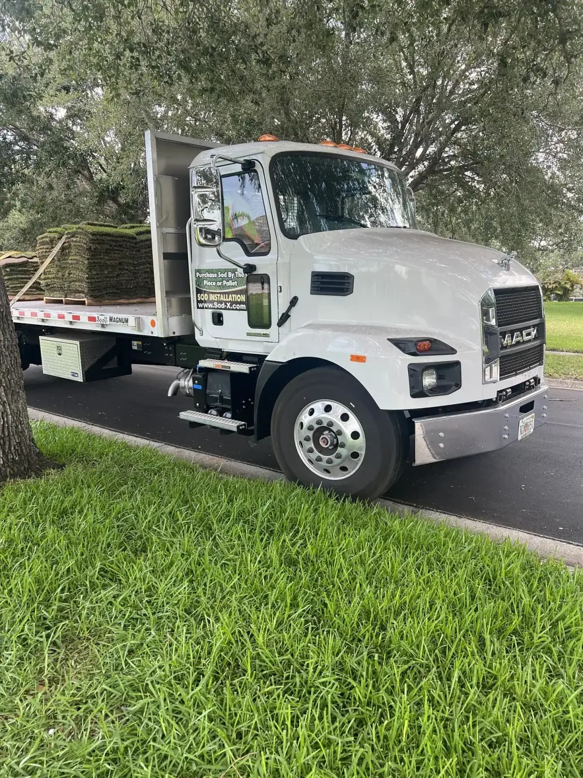 Un camión plano de Sod-X entregando pallets de césped en una casa de Tampa Bay